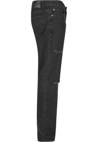 Mustat farkut slim fit -mallissa, joissa on kuluneita yksityiskohtia ja lievä kapenevuus lahkeessa, hopeiset yksityiskohdat ja teksturoitu pinta.