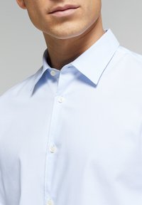 Lichtblauw overhemddesign met een gestructureerde kraag, manchetten met één knoop en gladde katoenstof. Heeft witte knopen langs de knopenlijst.