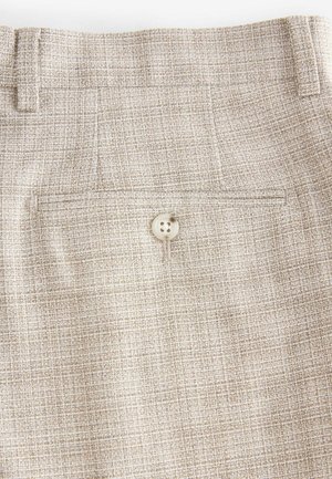Pantaloni beige chiaro in un tessuto testurizzato, con una tasca posteriore, chiusura con bottone e un delicato motivo a griglia in tutto il tessuto.
