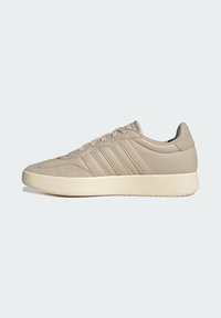 Beige lage sneaker met vetersluiting, drie zijstrepen en een dikke off-white zool op een effen lichte achtergrond.