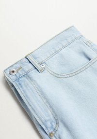 Jean en denim bleu clair plié, affichant la poche avant, la boucle de ceinture et un bouton argenté avec des détails de couture sur fond blanc.
