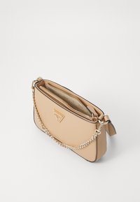 Beige crossbody veske med kjedehenkel, glatt tekstur, gullfarget hardware, glidelåslukking og logo-detalj foran, med en slank rektangulær form.
