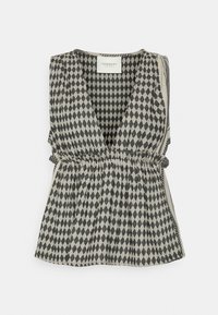 Top sin mangas de patrón de diamante en blanco y negro, con escote en V y cintura fruncida. Fabricado en tejido texturizado, presenta un corte holgado y lazos laterales.
