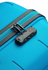 Valigia rigida di un vivace blu, con superficie testurizzata, zip nera con hardware metallico e lucchetto TSA sul lato.
