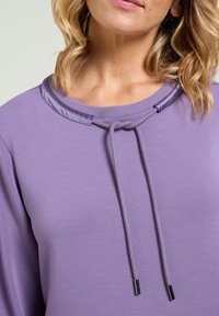 Felpa viola con scollatura rotonda, rifiniture in satin e corde regolabili con estremità metalliche. Tessuto liscio e texture.
