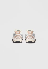 Sneaker bianche e grigio chiaro con un design testurizzato, accenti argento e dettagli perforati rosa. Presentano una suola in gomma nera.