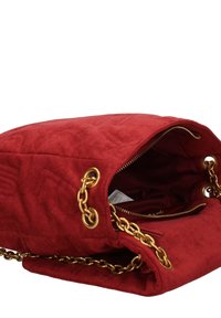 Sac à main en suède rouge avec un design matelassé, des anses en chaîne dorée, une fermeture zippée et une poche intérieure. Les accents comprennent des quincailleries et des coutures dorées.
