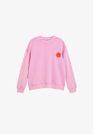 Rožinės spalvos medvilninis džemperis su apvalia iškirpte ir briaunuotais rankogaliais. Kairėje krūtinės pusėje siuvinėtas oranžinis gėlės raštas.