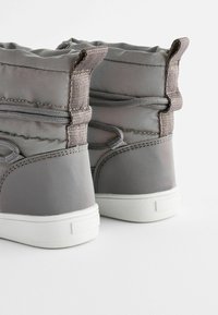Grijze laarzen met een gewatteerd ontwerp, voorzien van tonal stiksels, elastische veters en een witte rubberen zool. Versterkte achterkant voor ondersteuning.