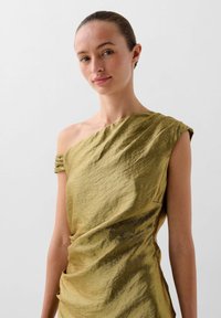 Olivengrün off-shoulder Kleid mit strukturierter Stoff, gerafften Details und asymmetrischem Design. Leichtgewichtig mit elegantem Fall.