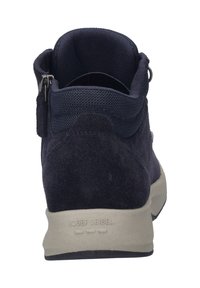 Laivansinis mokasīns līdz potītēm ar auduma kaklu, sānu rāvējslēdzis, mīkstināta iekšpuse un gaiši pelēja gumijas zole. Zīmola nosaukums iegravēts uz papēža.