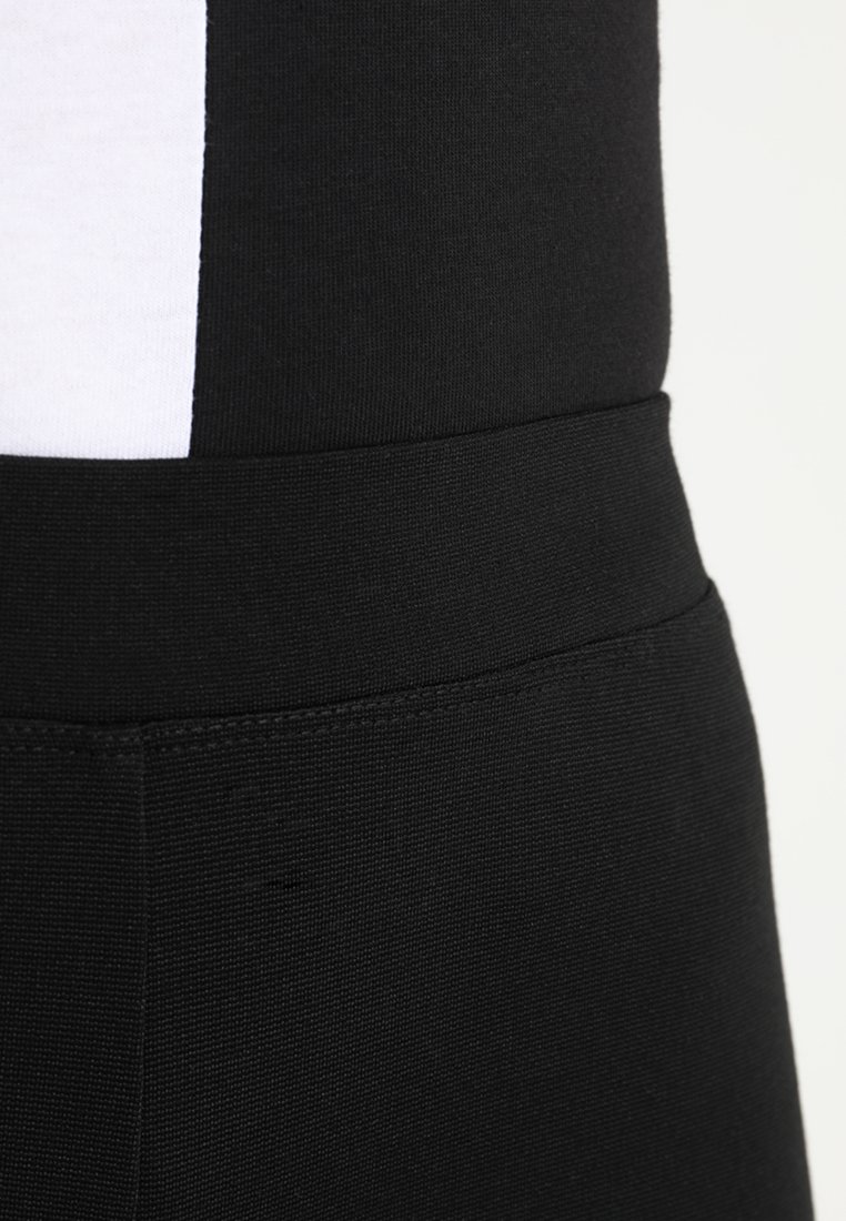 Czarne legginsy sportowe o gładkiej, elastycznej fakturze i szerokim pasku w talii. Zawierają biały akcentowy pasek po boku.