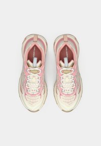 Zapatillas deportivas ligeras con una combinación de colores beige y rosa, que cuentan con un tejido texturizado, cordones blancos y una suela de goma duradera.