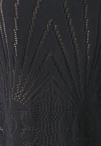 Tessuto a maglia nera con un motivo geometrico caratterizzato da texture variabili e dettagli a rete, creando un effetto visivo stratificato.