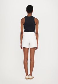 Top negro sin mangas con cuello redondo combinado con pantalones cortos blancos. Los pantalones cortos tienen una cinturilla elástica y una textura de tela suave.