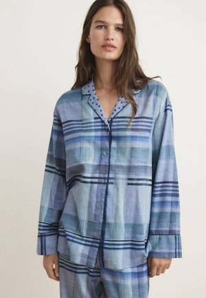 Pijamas de botones con un patrón de cuadros azules y un cuello de lunares. Corte holgado con mangas largas y líneas contrastantes en diferentes tonos de azul.