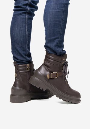Botas de tobillo de cuero marrón con acabado texturizado, cordones en el frente, cremallera lateral, detalle de hebilla y suela de goma con profundos surcos.