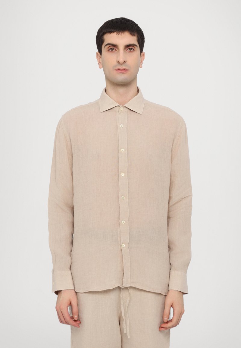 Camisa de linho bege claro com colarinho abotoado, botões à frente e mangas compridas. O tecido tem um acabamento ligeiramente texturizado.