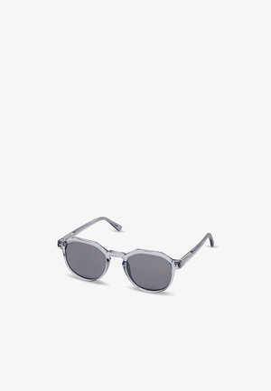 Sonnenbrille mit transparentem grauem Kunststoffrahmen und runden dunklen Gläsern, leicht schräg auf weißem Hintergrund.