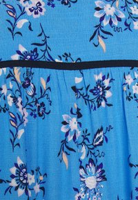 Tecido floral azul com padrões brancos e roxos, com pregas e uma cintura em contraste preta. Material leve e texturizado.