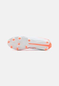 White soccer cleat with a textured upper, featuring a pink accent and orange studs, designed for grip on grass surfaces.