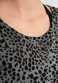 Šedá látka s černým leopardím vzorem a širokým, zaobleným výstřihem. Materiál vypadá měkký a mírně průhledný.