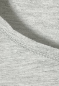 Grauer Baumwollstoff mit glatter Textur, ausgestattet mit einem runden Ausschnitt und sauberen, sichtbaren Nähten entlang der Kanten.