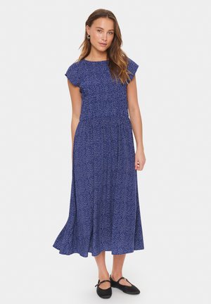 Blue midi dress with short flutter sleeves, featuring a textured pattern of white dots and a flowy hemline. Paired with black footwear.