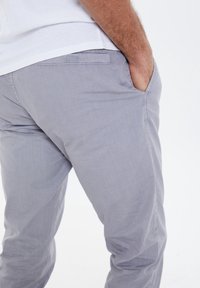 Hellgraue Chinos aus weichem Stoff, mit slim fit, seitlichen Taschen und einer Gesäßtasche mit einem dezenten Nähdetail.