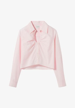 Blouse courte rose clair à manches longues avec col pointu, encolure en V froncée et fermeture boutonnée à l'avant.