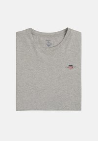 Gray cotton t-shirt with a crew neckline, featuring a small emblem in red, white, and blue on the left chest area. Folded flat.