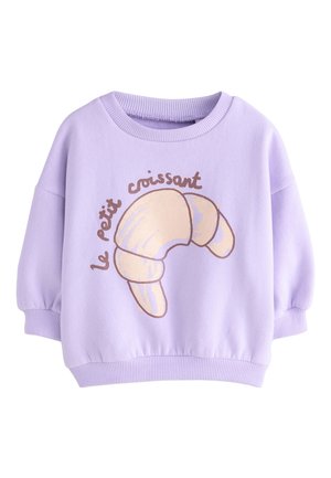 Liliowa bluza z długim rękawem z dużą beżową grafiką rogalika i brązowym napisem „le petit croissant” na piersi.