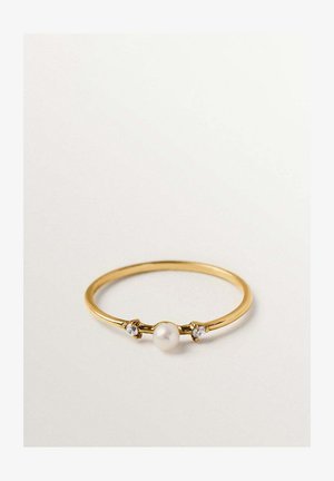 Anillo delgado de oro con una perla blanca central flanqueada por dos pequeñas piedras preciosas claras sobre un fondo blanco liso.