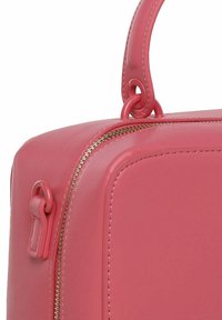Angolo di una borsa in pelle rosa con una texture liscia, caratterizzata da una cerniera dorata e da una maniglia corta e arrotondata per un facile trasporto.