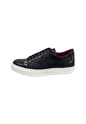 Zapatilla negra de cuero con textura trenzada en los laterales, suela de goma blanca y detalles en rojo, con ojetes redondos y cordones.