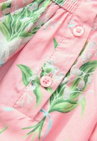 Růžová květinová košile s zelenými vzory konvalinek, nařaseným výstřihem a růžovými knoflíky s vyraženým nápisem "CANTERBURY".