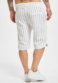 Shorts blancs à rayures avec une coupe décontractée, une taille élastique et une poche arrière. Le design est décontracté avec une longueur cropped.