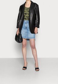 Svart läderblazer, grön camo-topp, ljusblå denimkjol med fransar, och svarta sandaler. Liten quiltad svart handväska.