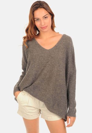 Gray ribbed sweater with a deep V-neck, long sleeves, and a relaxed fit, paired with light-colored shorts. Textured knit material.