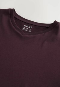Maroon v-ringad t-shirt i en vanlig passform, tillverkad av mjuk bomullstyg. Har en enkel, odekorerad design med synliga sömmar.