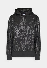 Black hoodie with shiny, embossed text in various sizes. Features a drawstring hood and ribbed cuffs and hem. Soft fabric texture.