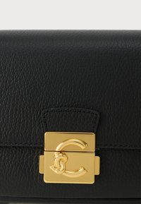 Zwart leren handtas met een gestructureerde afwerking, voorzien van een gouden metalen sluiting en logo-accent aan de voorkant. Compacte rechthoekige vorm.