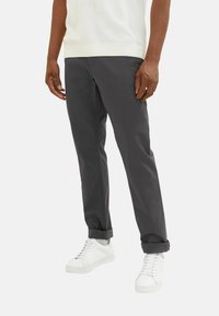 Graue Baumwollhosen mit geradem Schnitt, mit hochgeschlagenen Säumen und Seitentaschen, kombiniert mit weißen Sneakers.