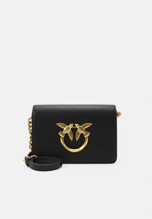 Sort læder crossbody taske med guldkæde og dekorativ guldring med to fugle, der vender mod hinanden på frontklappen.