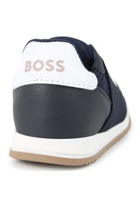 Sneaker blu navy con superiore in tessuto testurizzato, dettagli in pelle bianca e suola in gomma. Presenta il marchio "BOSS" in metallo sul tallone.