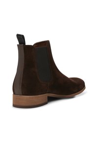 Bottines Chelsea en suède marron avec des panneaux latéraux élastiques, une languette à l'arrière et une semelle en bois clair. Texture lisse avec des détails de design minimalistes.