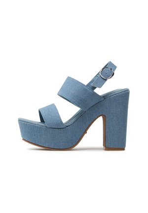 Sandalia de plataforma de mezclilla azul con dos tiras anchas, hebilla en el tobillo y tacón alto grueso sobre fondo blanco.