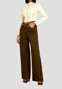 Woman wearing a cropped cream jacket with zipper details, brown wide-leg pants, a designer belt, and brown platform sandals.