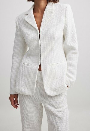 Weißer strukturiertes Blazer mit Reverskragen, einem Knopfverschluss und zwei frontalen Taschen, kombiniert mit passenden schmal geschnittenen Hosen.