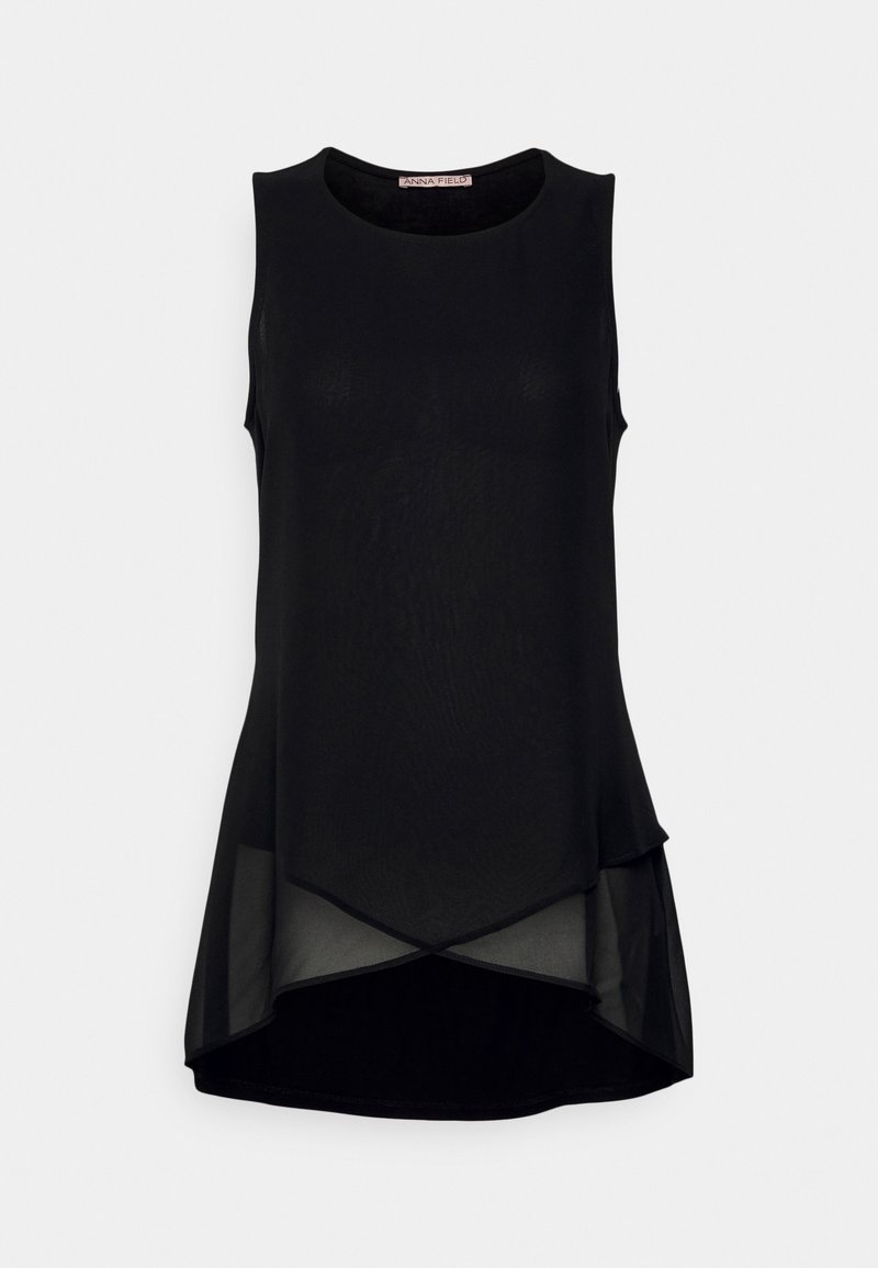 Blouse noire sans manches avec tissu transparent superposé et ourlet asymétrique, présentant un col rond.